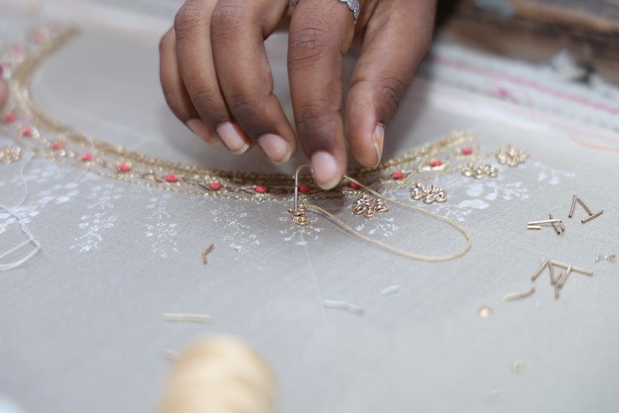 Close-up of hands stitching zari embroidery on cloth