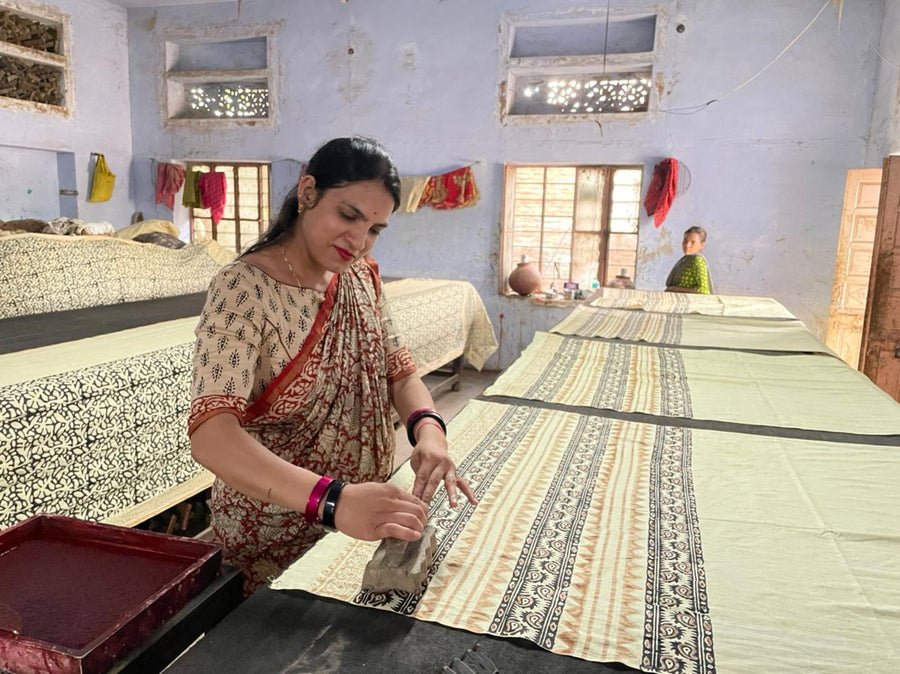 A woman block printing cloth at a long printing table in Bagru, near Jaipur